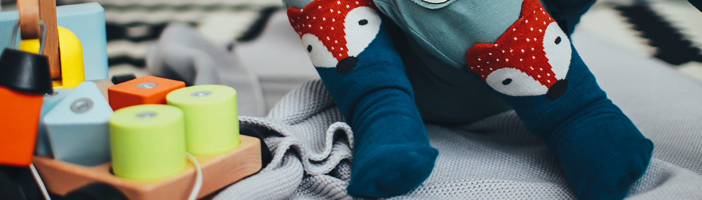 Kleinkind mit Holzspielzeug und Fuchssocken